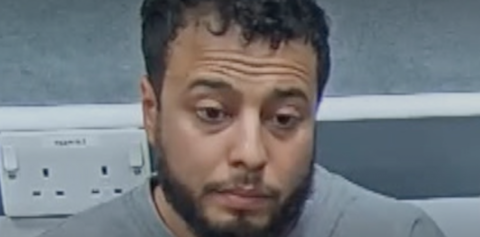 Walid Saadaoui is wearing a grey prison sweatshirt as he is interviewed by police