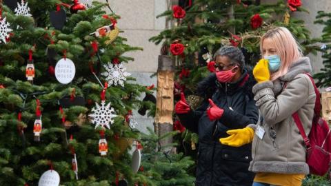 Women in face masks looking at Christmas trees