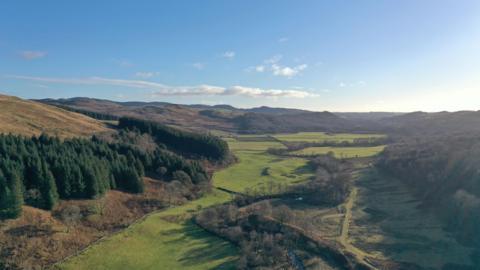 The rolling hillside of Galloway viewed from above with trees and large fields