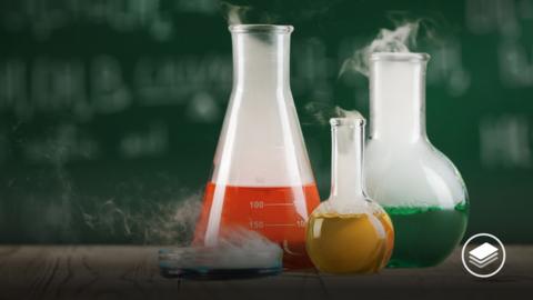 A photograph of science beakers, all with different colour liquids inside of red, yellow, green and blue.