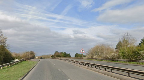 A road leading through some trees with a blue sky above.