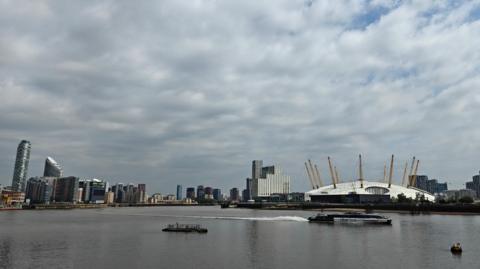 A cloudy sky over the Millennium Dome, skyscrapers and the River Thames