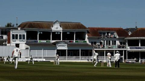 The Spitfire Ground with cricketers playing dressed in all white, with blue sky
