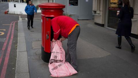 Postman empties a letter box