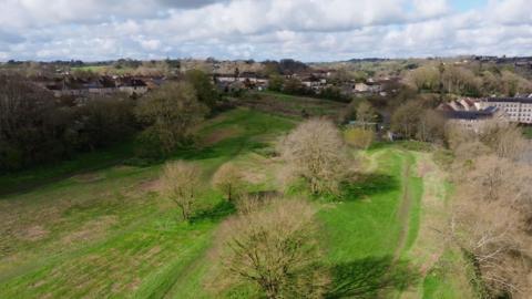 An aerial view of the old golf course with lots of trees surrounding it 