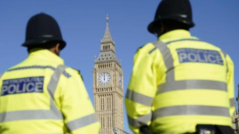 Two male officers with backs to camera facing Big Ben