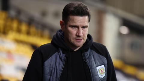 Crewe Alexandra manager Lee Bell stares towards the ground as he walks towards the dressing room after a match