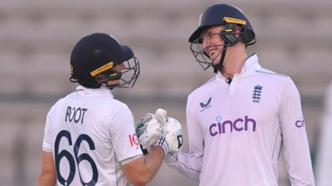 Zak Crawley and Joe Root clench gloves in the first Test against Pakistan