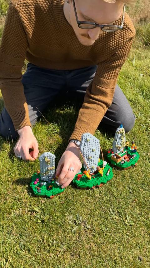 Man in brown jumper building Lego standing stones