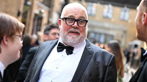 Cliff Parisi in a tuxedo and glasses.