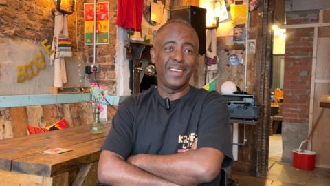 Coffee shop owner sat in his shop.