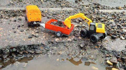 A toy digger at a pothole