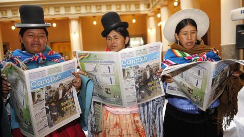 Three "cholas" (women belonging to the Aymara ethnic group) read the government's official newspaper "Cambio" in La Paz
