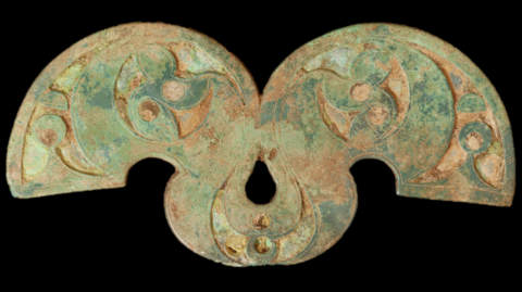 A turquoise- and copper-coloured brooch with some ornamentation.