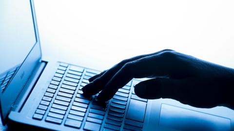 A person uses one hand to type on a laptop device. 