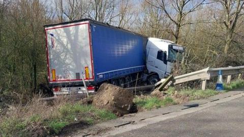 A lorry on a grass area next to the M25 after crashing through a barrier.