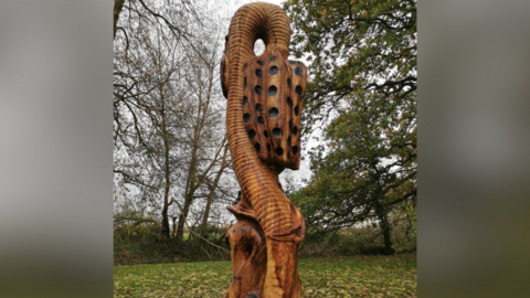 The wooden sculpture depicting a snake's head fritillary.
