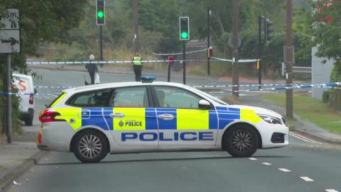 Police car across road and blue and white tape as police cordon near scene of stabbing in Monk Bretton