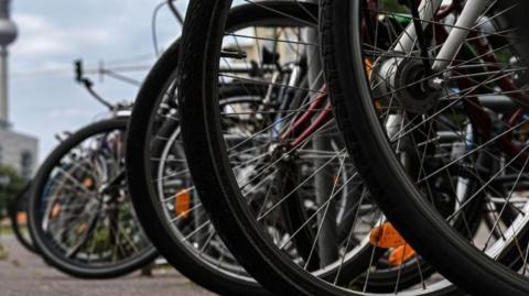 A close up image of a numerous bike wheels on a street. 