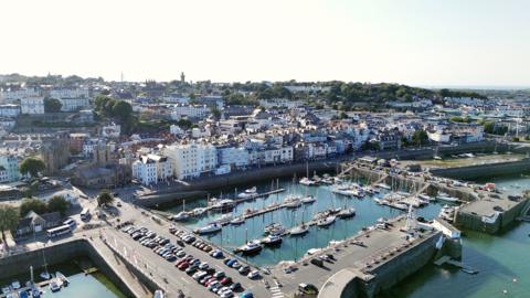 Aerial view of St Peter Port. Buildings and harbour in view.