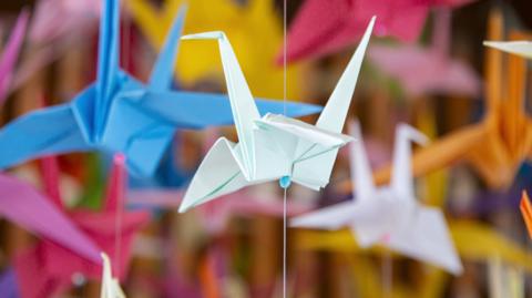 Colourful origami paper cranes hanging in a display