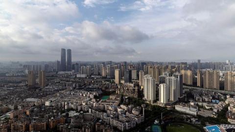 The skyline of the Chinese city of Kunming, with numerous high rises and mid-rise buildings. It is a cloudy day