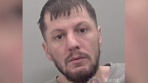 A police custody image of a man with a beard 