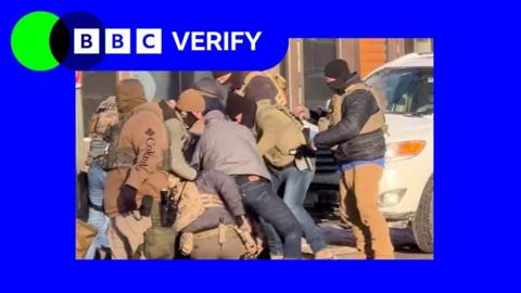 ICE agents surrounding a man on the street.