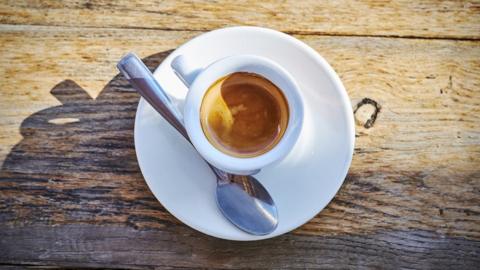 A cup of espresso coffee on a table, seen from above.