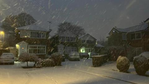 Houses with driveways and cars covered in snow