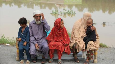 People wait for relief at a flooded area in Charsadda District, Khyber Pakhtunkhwa province, Pakistan, 27 August 2022.