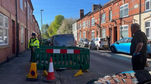 Police working on a residential street with an area surrounded by barriers and cones