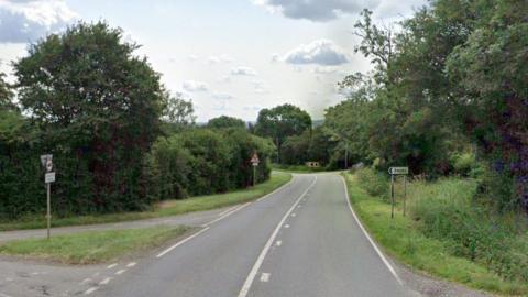 A general street view of the A6006 in Leicestershire near Shoby. There is a small signpost on the right of the road, opposite a junction on the left, which reads 'Shoby' 