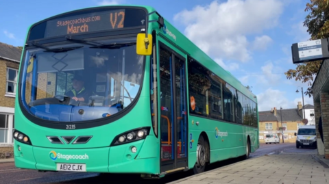 Stagecoach green bus with March on its destination banner stops at a bus stop
