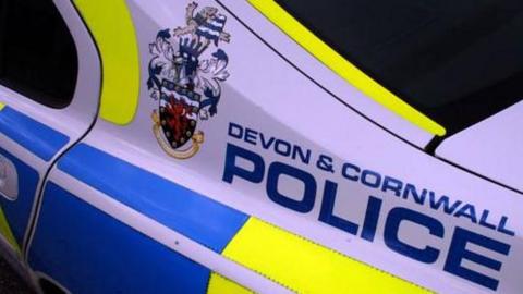 The side of a police car with lettering reading Devon and Cornwall Police