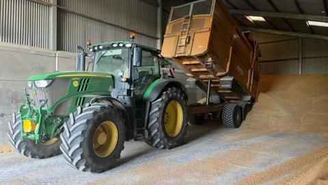 A tractor offloads harvested grain