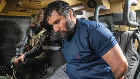 Adolfo Macias Villamar 'Fito' (R) is guarded as he is moved in Guayaquil, Ecuador, 25 June 2025