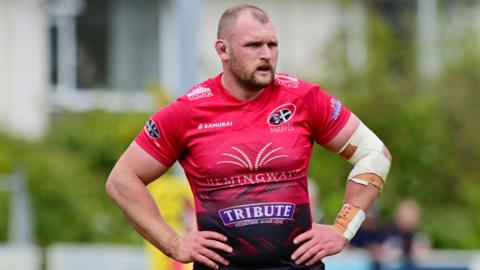Alex Everett of Cornish Pirates standing on the pitch with both of his hands on his hips and his arms bent 