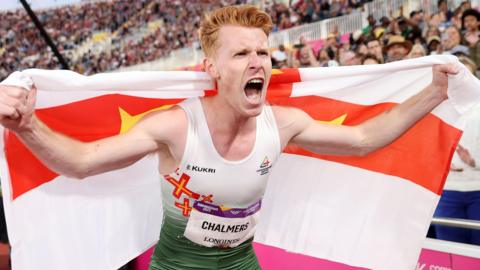 Alastair Chalmers celebrates holding a Guernsey flag