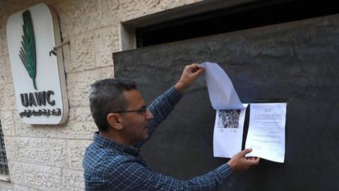 A man reads an Israeli military order posted on an iron door installed by soldiers at the entrance of the Union of Agricultural Workers Committees (UAWC) office in Ramallah, in the occupied West Bank (18 August 2022)