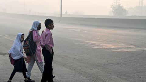 Three children cross the road in Lahore 