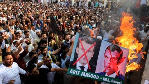 Indian Muslims hold placards as they protest against French President Emmanuel Macron