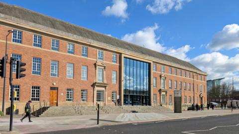 Large rectangular organge brick building with tall glass windows