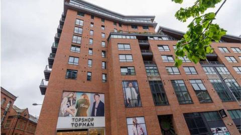 The apartments at Victoria Square in Belfast, Chichester Street, they are a red brick building - with a sign for Topshop Topman at the bottom of the building 