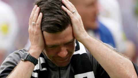 An emotional Darrell Clarke with his head in his hands after beating Mansfield Town