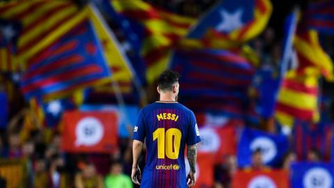 Player Lionel Messi of Barcelona football club looks on as Catalan pro-independence flags are seen in the background