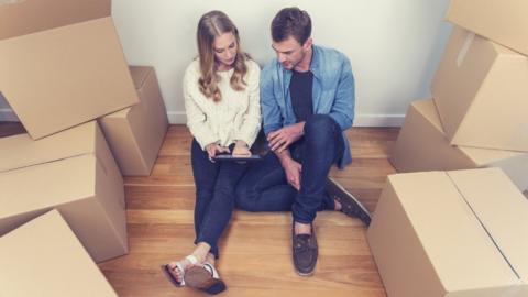 Young woman and man sat on the floor surrounded by boxes