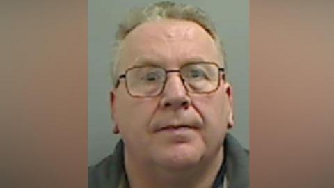 Mugshot of Coupland. He is clean shaven with glasses and short thin fair hair.