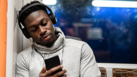 A man listens to music using his mobile phone