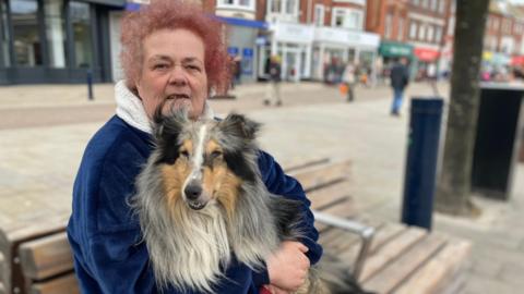 A woman sits on a bench with her dog Cody in Great Yarmouth's Market place